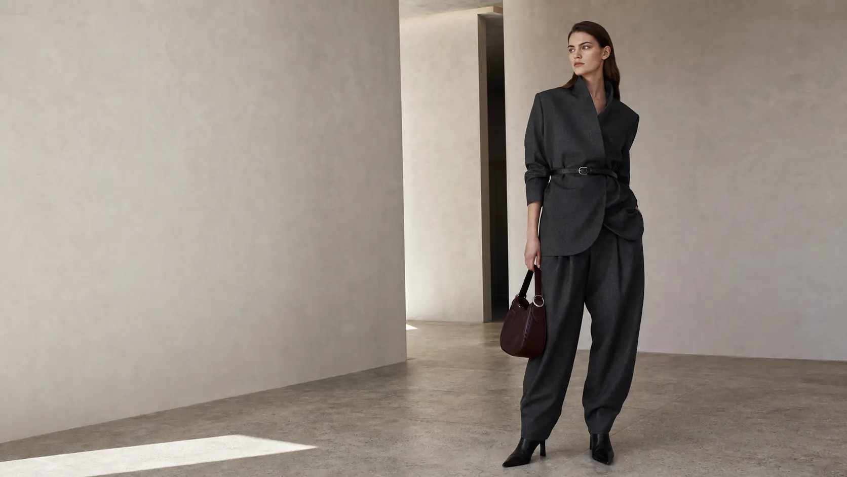 Model wearing charcoal tailoring in a contemporary gallery